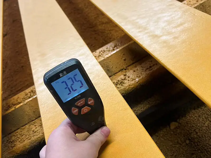 Dry film thickness gauge measuring A65 crane rail coating after epoxy primer and polyurethane topcoat application