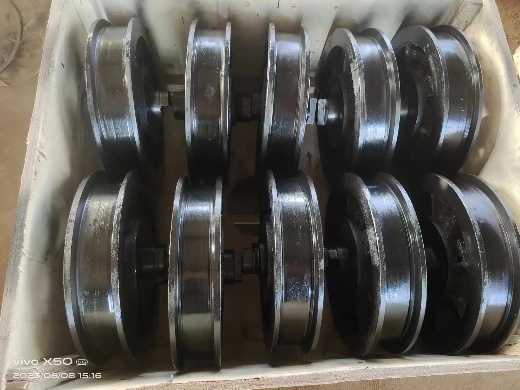 Cast bogie wheel production batch showing machined double-flange wheels in wooden shipping crate