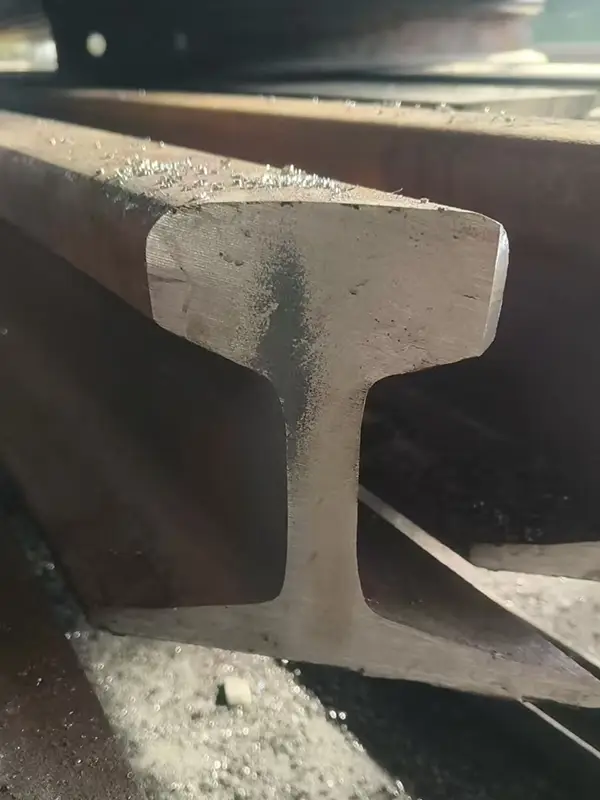 Close-up of S49 steel rail showing 45-degree bevel cut with 5mm chamfer detail